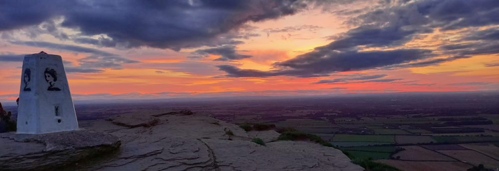 Picture from the top of Roseberry Topping at sunset. The cairn has a portrait of the late queen Elizabeth II